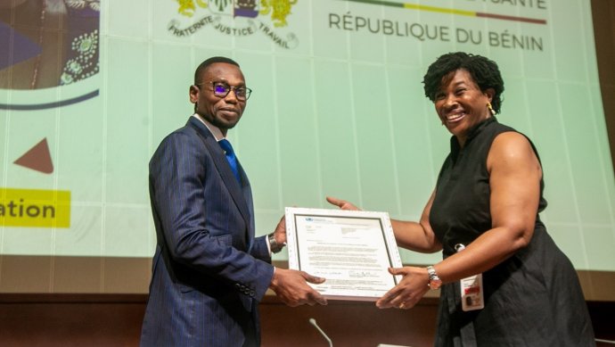 The WR-Benin, Dr. Renee Tania Bissouma-Ledjou, presents Dr. Benjamin Hounkpatin, Minister of Health of Benin with the validation letter